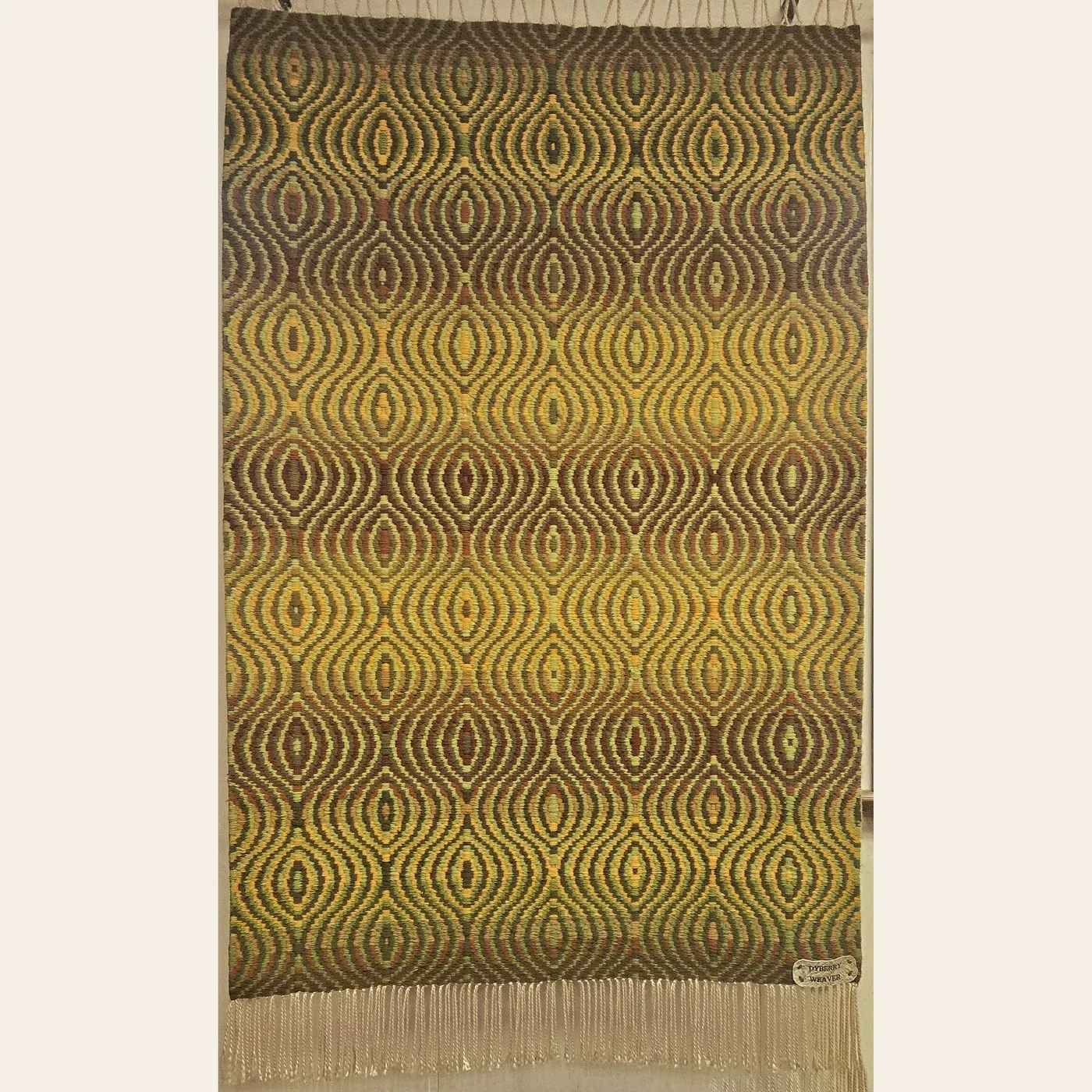 Hand-woven rug by Charles H. Blanchard, the Dyberry Weaver of Narrowsburg NY, in an undulating ogee pattern of olive green, gold and brown with cream fringe