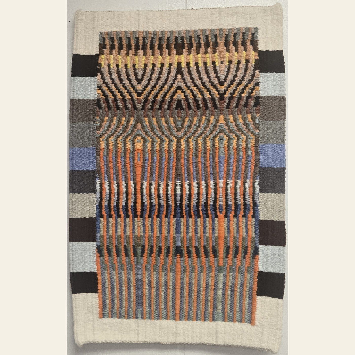Hand-woven tapestry by Charles H. Blanchard, the Dyberry Weaver of Narrowsburg NY, with mirrored arch patterns in orange, indigo, gold and charcoal framed by a cream border
