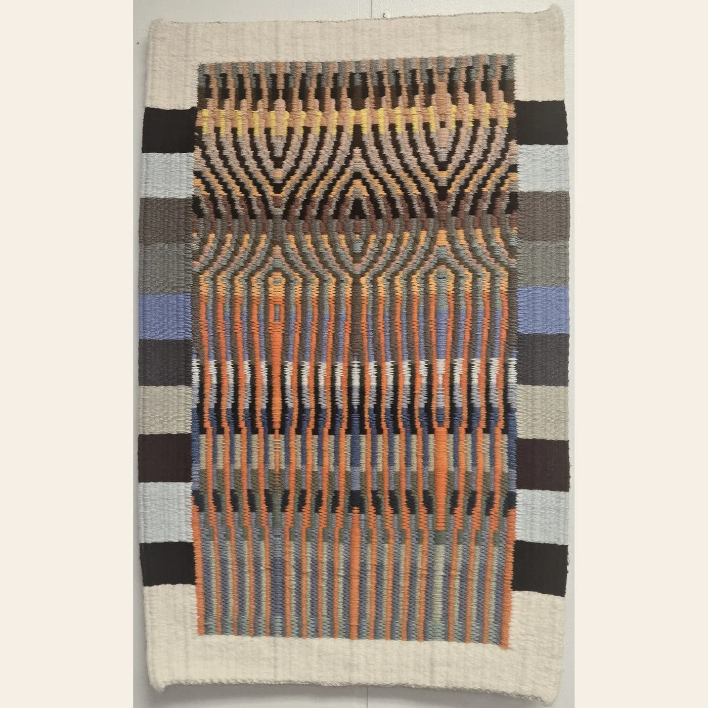Hand-woven tapestry by Charles H. Blanchard, the Dyberry Weaver of Narrowsburg NY, with mirrored arch patterns in orange, indigo, gold and charcoal framed by a cream border